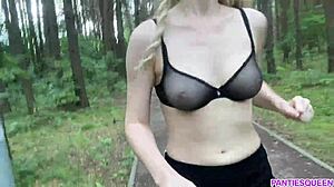 Blondýnka cvičí venku v parku, odhaluje své nahé tělo a poskakuje prsy